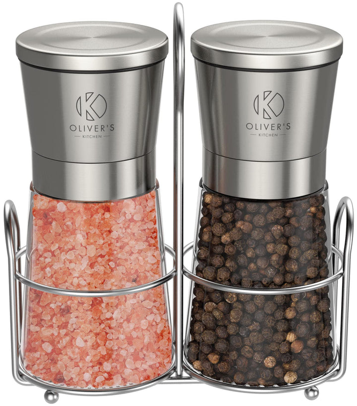 Glass salt and pepper mills with stainless steel tops on a matching stand, filled with pink salt and black peppercorns