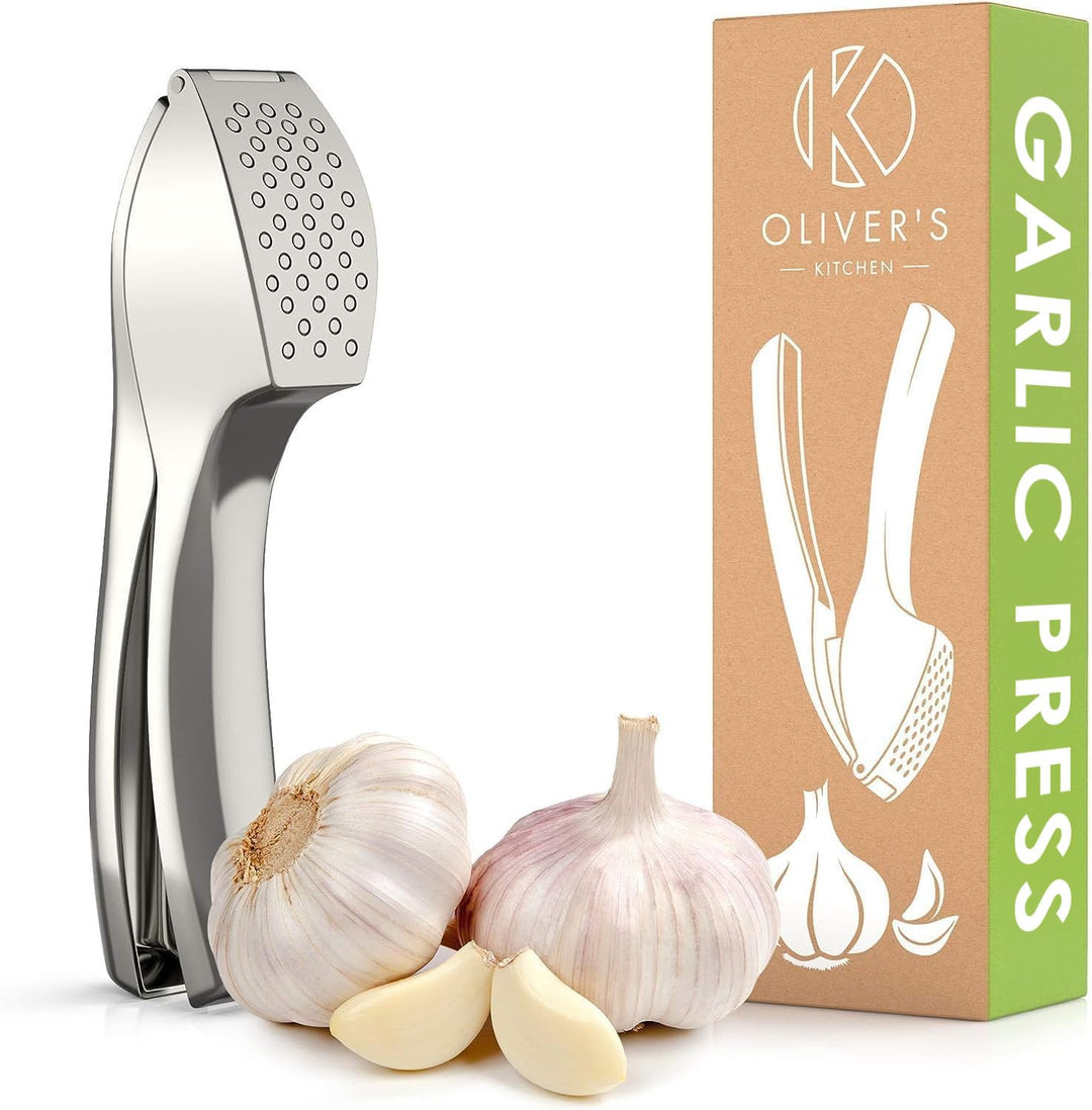 Garlic press in silver by Oliver's Kitchen with its kraft card box and fresh garlic bulbs