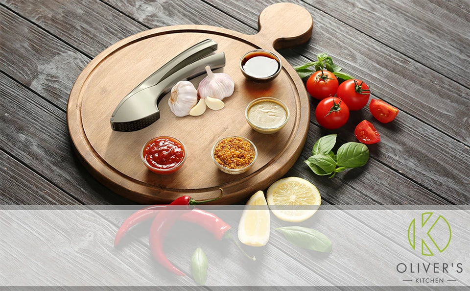 Strong zinc alloy garlic press on a bamboo board with garlic cloves, tomatoes and spices